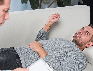 Man lying on couch, looking distressed or in pain.
